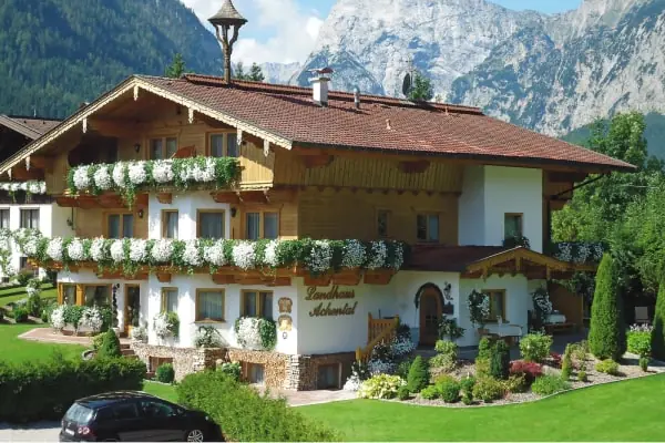 Landhaus Achental mit Blumenbalkonen vor Bergkulisse
